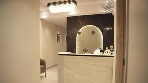 Ein Empfangsbereich mit Marmor-Theke, einem großen Spiegel und einer Chandelier.