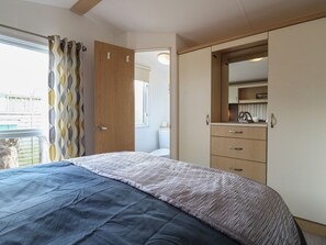 A bedroom with a bed, a wardrobe, a bathroom, and a view of the outside. - Debonair Atlas Caravan Rental Stonham Barns (Stowmarket)