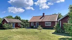Punatiilinen talo, jossa on tiilikatto, nurmikko ja pieni puutarha-alue.