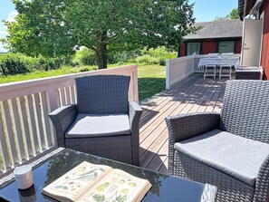 Eine Terrasse mit Korbmöbeln und einem Tisch mit einem Buch und einer Tasse.