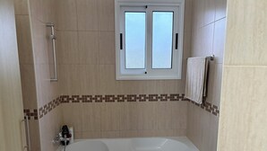 Un bagno con una vasca, una finestra e un porta asciugamani.