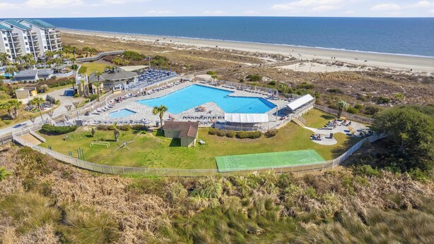 Un complexe hôtelier doté d’une grande piscine, d’un court de tennis et offrant une vue sur la plage.