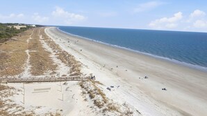 Une plage avec une promenade en bois et quelques personnes.