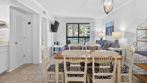 Un coin repas avec une table et des chaises, un téléviseur fixé au mur et une vue par la fenêtre.