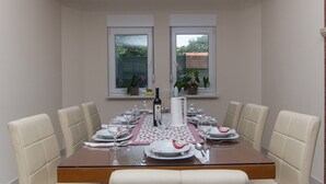 A dining area with a table set for four, two windows, and potted plants. - Holiday Home Vele with pool (Vrgorac)