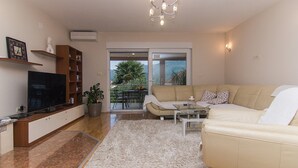 A living room with a sofa, TV, bookshelf, and a potted plant. - Holiday Home Vele with pool (Vrgorac)