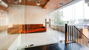 A modern interior with a glass wall, a wooden ceiling, a black floor, and a red sofa. - Classic With Balconyhaldwani INN (Haldwani)
