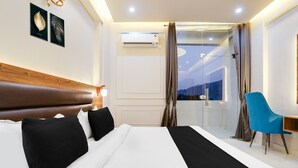 A hotel room with a bed, a desk, a chair, an air conditioning unit, and a view of the outdoors. - Classic With Balconyhaldwani INN (Haldwani)