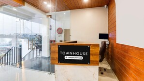 A reception desk labeled 'TOWNHOUSE' with a company-serviced sign, a glass wall, a wooden ceiling, and a view of a bridge. - Classic With Balconyhaldwani INN (Haldwani)