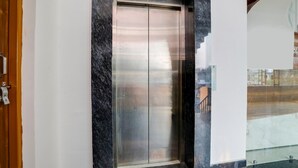 An elevator with a metallic finish, a marble wall, and a wooden door frame. - Classic With Balconyhaldwani INN (Haldwani)