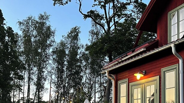 En rød bygning med veranda, trapper og udendørs siddepladser.