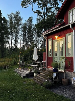 En rød bygning med veranda, trapper og udendørs siddepladser.