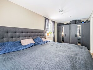 A bedroom with a tufted headboard, a bed with patterned bedding, a wardrobe, and a ceiling fan. - Paradislyckan by Interhome (Huddinge)