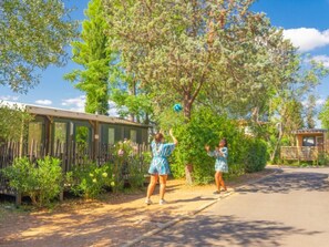 A residential street with a house, a wooden fence, and a tree. - Mobile home with AC - 4 guests (Balaruc-les-Bains)