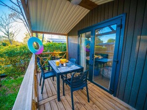 Une terrasse extérieure couverte, équipée d’une table et de chaises, d’un barbecue et d’une porte-fenêtre coulissante.