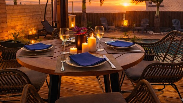 A round dining table set for four with candles, glasses, and a vase of flowers. - Lodge with shared pool - 4 guests (Le Tampon)