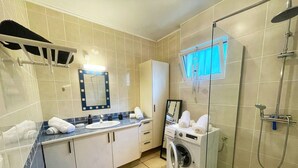 A modern bathroom with a sink, mirror, towel rack, shower, and a washing machine. - Lodge with shared pool - 4 guests (Le Tampon)