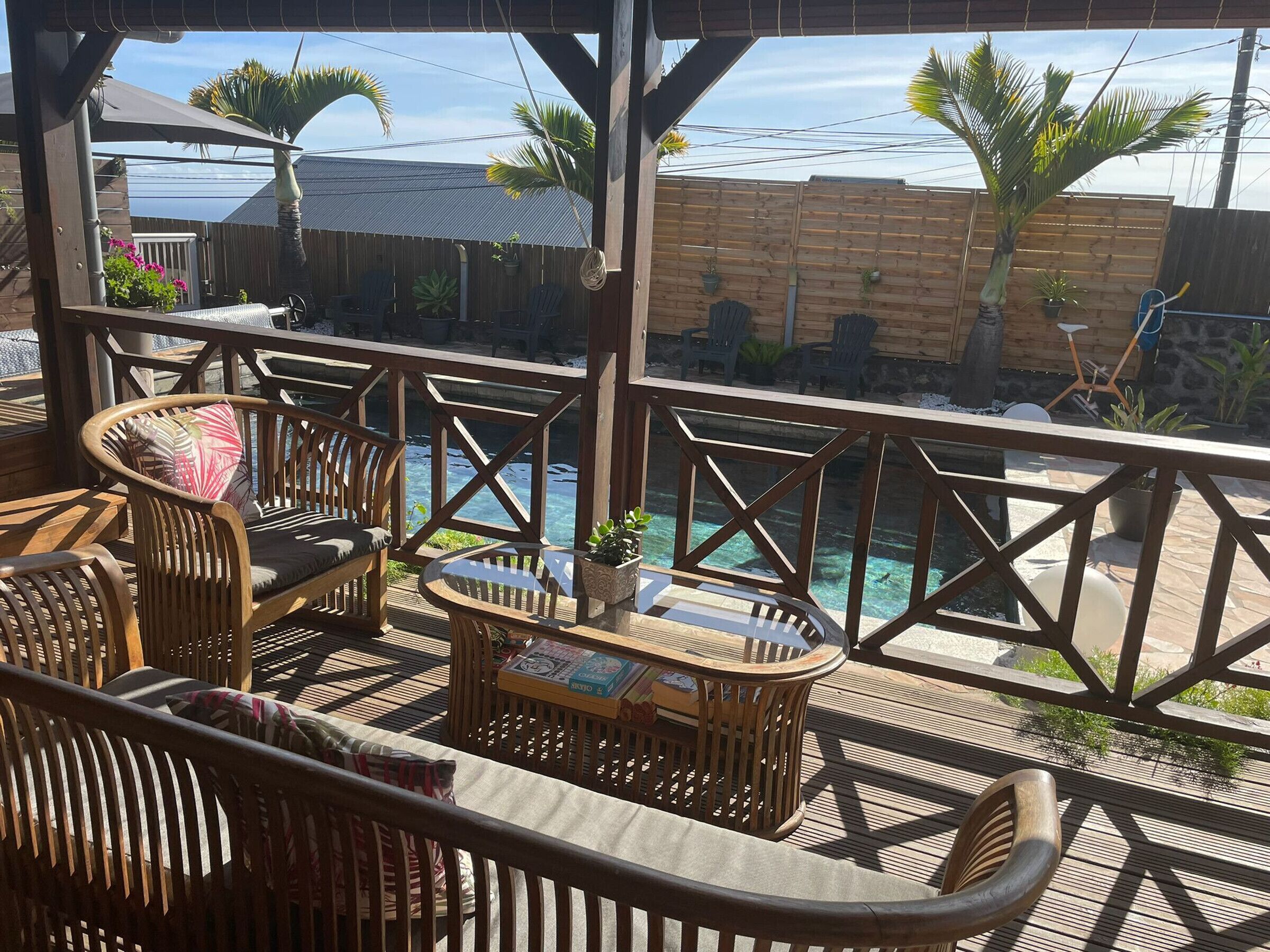 A wooden deck with outdoor furniture, a pool, and a view of the ocean.