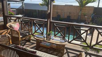 A wooden deck with outdoor furniture, a pool, and a view of the ocean.