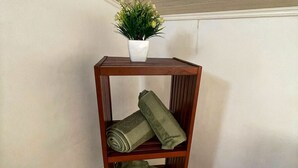 A wooden shelf with a potted plant and folded towels. - Peaceful lodging in Tampon, ocean view - 2 guests (Le Tampon)