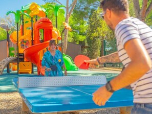 Un parque infantil con un tobogán, estructuras para escalar y una mesa de ping pong.