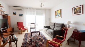 Ein Wohnzimmer mit einer Couch, Sesseln, einem Couchtisch, einem Fernseher und einem gemusterten Teppich.