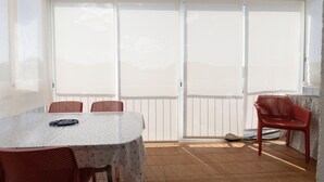Ein Zimmer mit Tisch, Stühlen, einem Deckenventilator und einer Schiebetür.