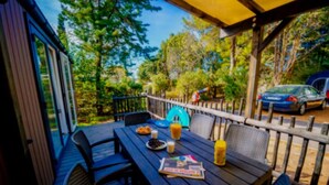 An outdoor patio with a wooden table, chairs, and a yellow awning. - Mobile home with AC - 6 guests (Balaruc-les-Bains)