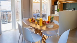 A modern kitchen with wooden cabinets, a dining table with chairs, and a breakfast spread. - Mobile home with AC - 6 guests (Balaruc-les-Bains)