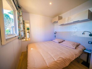 A bedroom with a bed, a bedside table, a mirror, and a window with curtains. - Cottage with AC, pets allowed - 6 guests (Balaruc-les-Bains)