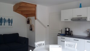 Una cocina moderna con armarios blancos, una cafetera y un comedor con mesa y sillas blancas.