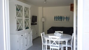 Una habitación con una mesa de comedor, sillas, un aparador con puertas de cristal, una lámpara y un cuadro en la pared.
