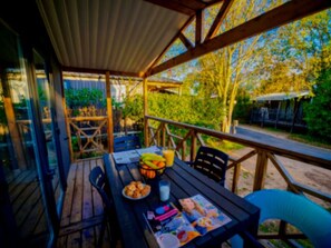 An outdoor dining area with a table set for two, a bowl of fruit, and a magazine. - Spacious cottage with AC - 8 guests (Balaruc-les-Bains)