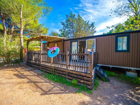 Een houten vakantiehuis met terras, raam en deur.