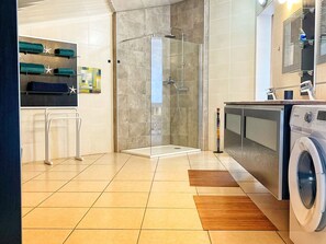 A modern bathroom with a glass shower enclosure, a washing machine, and a sink with a mirror. - Lodging with pool, sea view - 4 guests (Le Tampon)
