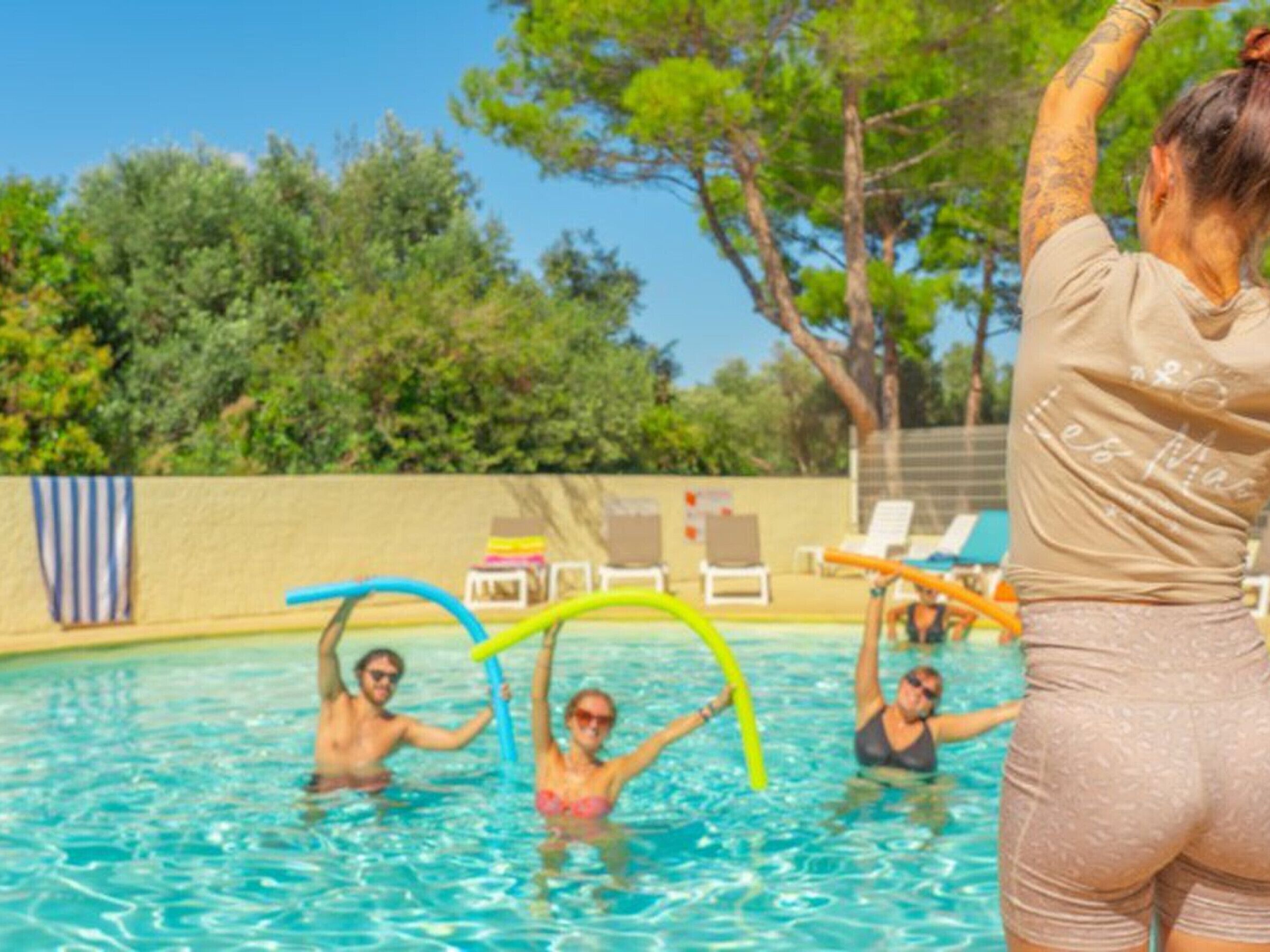 A swimming pool with people, lounge chairs, and a poolside area.