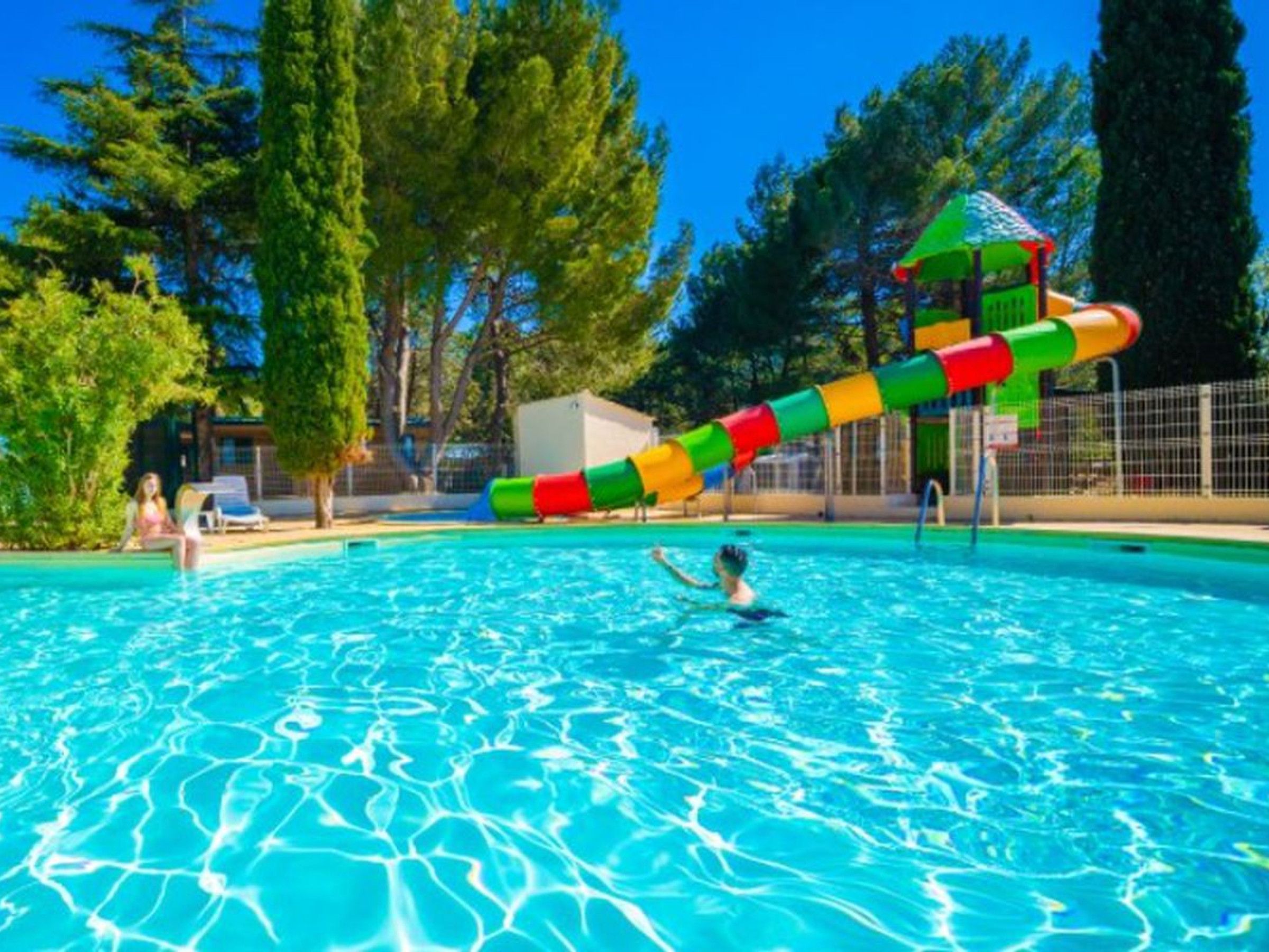 En swimmingpool med en färgglad vattenrutschkana och en liten tornliknande konstruktion.