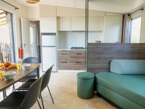 A compact living space with a dining area, kitchenette, and a sofa. - Air-conditioned mobile home - 6 guests (Balaruc-les-Bains)