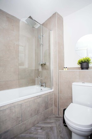 A modern bathroom with a glass-enclosed shower, a white toilet, and a small potted plant on the wall. - Vacant Nests | The Freda | Modern 3BR Home | (Sunderland)
