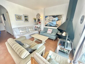 Ein Wohnzimmer mit einer Couch, einem Couchtisch, einem Bücherregal, einem Gemälde und einem Fernseher.