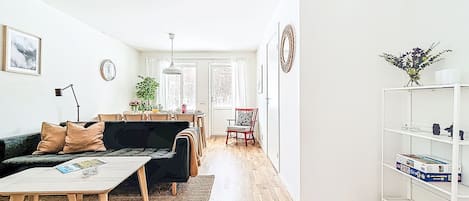 A modern living room with a sofa, coffee table, and a dining area with chairs and a table.