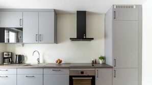 Una cocina moderna con gabinetes grises, un horno de acero inoxidable, un microondas y una cafetera.