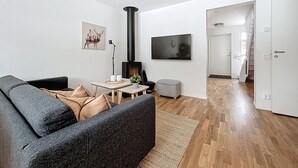Una sala de estar moderna con un sofá, un televisor, una chimenea y una escalera que lleva a otra habitación.