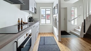 Una cocina moderna con horno empotrado, cafetera y ventana con vistas a un edificio rojo.