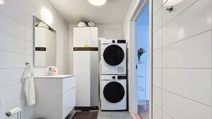 Un baño pequeño con inodoro, lavabo, espejo y lavadora de pared.
