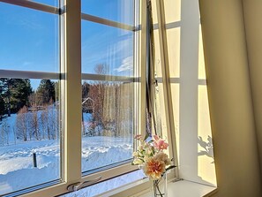 A window with a view of a snowy landscape, a clear sky, and a vase with flowers on the windowsill. - Svanhågna Gård by Interhome (Lofsdalen)