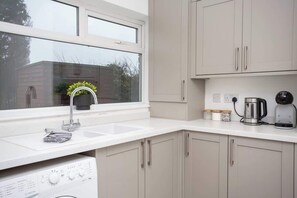 Una cocina moderna con lavavajillas incorporado, ventana con vistas y una cafetera sobre la encimera.
