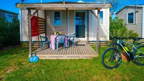 A mobile home with a covered porch, a table with chairs, and a bicycle parked outside. - Mobile-home with AC - 4 guests (Frontignan)