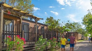 A row of wooden cabins with a gravel path, surrounded by greenery and flowers. - Mobile home, pets allowed, AC - 6 guests (Frontignan)