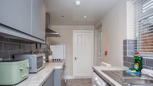 A compact kitchen with a microwave, toaster, and washing machine.